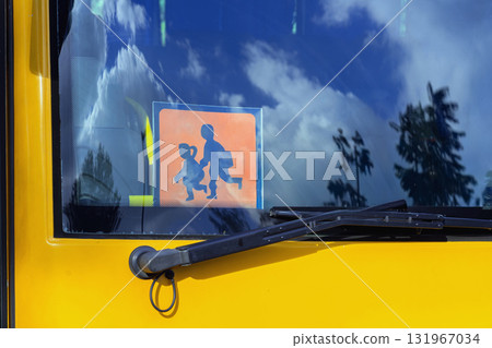 Orange school bus with of School Going Children sign visible through windshield with blue sky reflection. Concept of road safety, school transport, child protection Orange school bus with of School Going Children sign visible through windshield with blue sky reflection. Concept of road safety, school transport, child protection 131967034