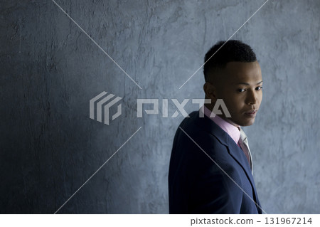 Man in suit standing against wall Man in suit standing against wall 131967214