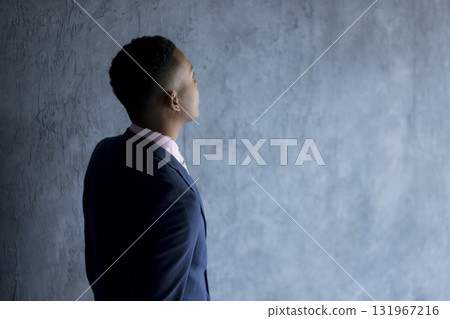 Man in suit standing against wall Man in suit standing against wall 131967216