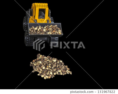 A creative and unique macro studio shot of a miniature yellow and grey plastic toy construction front loader, isolated against a dramatic black background, scooping a mound of whole black peppercorns. A creative and unique macro studio shot of a miniature yellow and grey plastic toy construction front loader, isolated against a dramatic black background, scooping a mound of whole black peppercorns. 131967822
