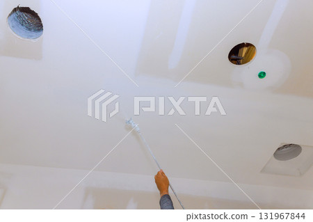 Worker is painting ceiling with using spray home improvement task in progress. Worker is painting ceiling with using spray home improvement task in progress. 131967844