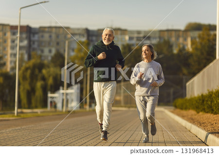 Fit senior man and woman jogging together on outdoor morning sports workout in city 131968413