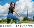 A woman riding a bicycle under a clear blue sky and smiling 131968760