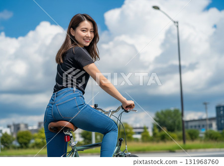一位女士在晴朗的藍天下騎著自行車,面帶微笑 一位女士在晴朗的藍天下騎著自行車,面帶微笑 131968760