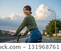 A woman riding a bicycle down a street at dusk 131968761