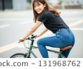 A woman looking back and smiling while riding a bicycle through the city 131968762