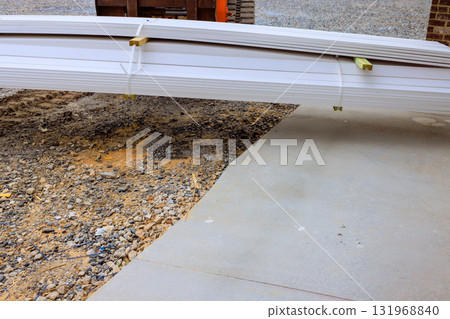 Stacked building materials rest at construction site on gravel surface under works day Stacked building materials rest at construction site on gravel surface under works day 131968840