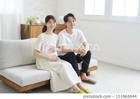 Couple in their 20s, pregnant wife, portrait, home, no eye contact Couple in their 20s, pregnant wife, portrait, home, no eye contact 131968844