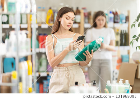 Woman scanning a package of detergent on her phone 131969395