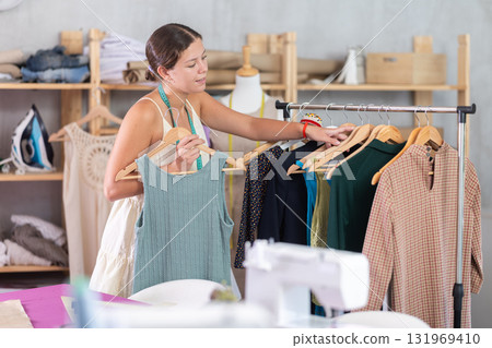Girl seamstress shows finished dress. Girl seamstress shows finished dress. 131969410