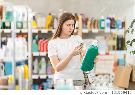 Girl buyer scans qr code on liquid powder label Girl buyer scans qr code on liquid powder label 131969413