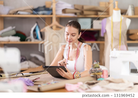 Woman dressmaker drawing on tablet 131969452