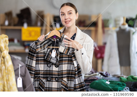 Adult woman chooses coat in clothing store Adult woman chooses coat in clothing store 131969590