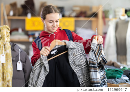 Teenage girl chooses coat in clothing store Teenage girl chooses coat in clothing store 131969647