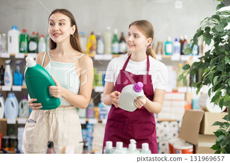 woman, with the help of a supermarket seller, chooses a detergent woman, with the help of a supermarket seller, chooses a detergent 131969657