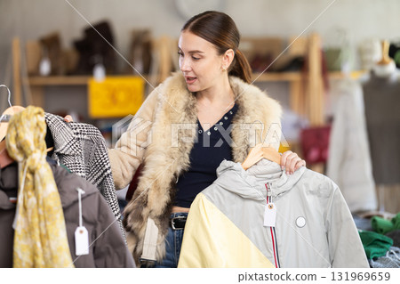 Adult woman chooses down jacket in clothing store 131969659