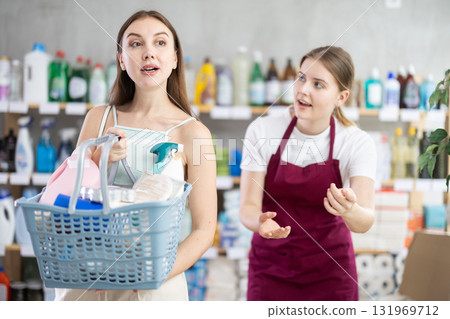 Woman with a full basket of household chemicals is standing near the seller 131969712