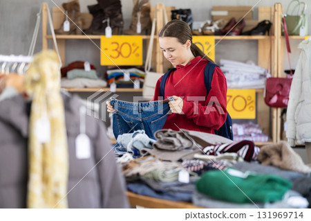 Teenage girl choosing jeans in clothing store Teenage girl choosing jeans in clothing store 131969714