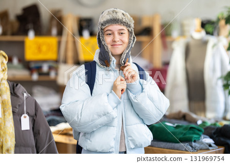 Glad teenage girl trying fur hat in clothing store 131969754
