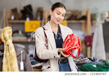 Happy woman standing in interior of clothing boutique and choosing fashionable handbag. Black Friday sale Happy woman standing in interior of clothing boutique and choosing fashionable handbag. Black Friday sale 131969787