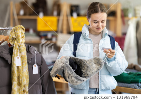Teenage girl choosing fur hat in clothing store 131969794