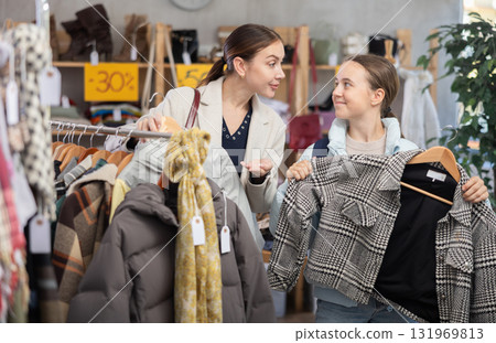 Woman and daughter choosing coats and jackets in the store Woman and daughter choosing coats and jackets in the store 131969813