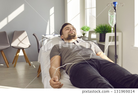 Young male patient lying on medical bed and receiving intravenous medication infusion Young male patient lying on medical bed and receiving intravenous medication infusion 131969814