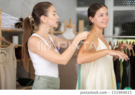 Young female dressmaker measuring woman client 131969815