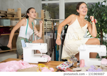 Two young seamstresses doing exercises during break Two young seamstresses doing exercises during break 131969887