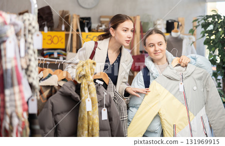 woman and her daughter choose a down jacket in a store woman and her daughter choose a down jacket in a store 131969915