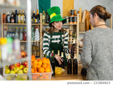 Friendly saleswoman in St. Patricks hat assisting customer with beer selection Friendly saleswoman in St. Patricks hat assisting customer with beer selection 131969923