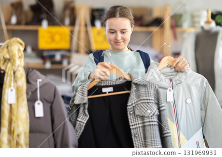 Teenage girl chooses outerwear in store Teenage girl chooses outerwear in store 131969931