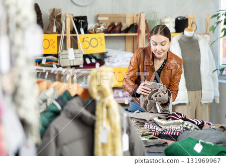 Young woman choosing trousers in clothing store Young woman choosing trousers in clothing store 131969967