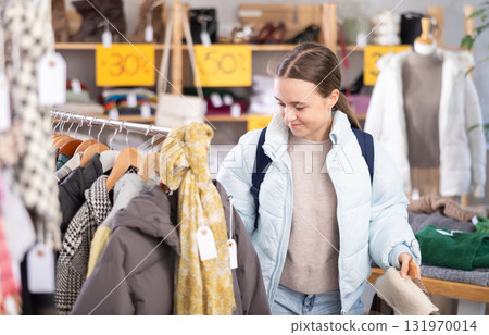 Teenage girl chooses outerwear in store Teenage girl chooses outerwear in store 131970014
