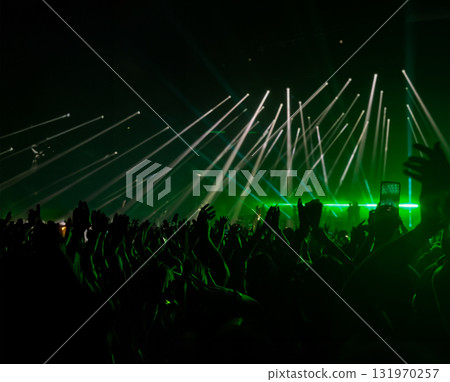 A crowded concert hall with scene stage lights in green tones. Horizontal shot.Copy space A crowded concert hall with scene stage lights in green tones. Horizontal shot.Copy space 131970257