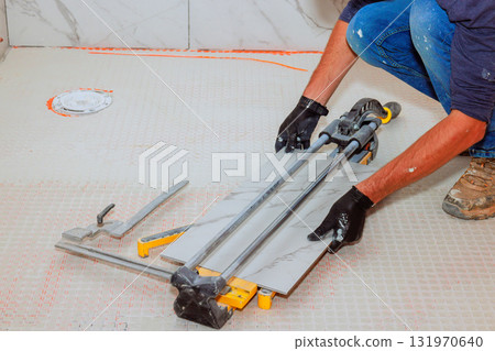 Worker on cutting large marble tile on floor in busy construction bathroom Worker on cutting large marble tile on floor in busy construction bathroom 131970640