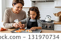 Grandmother and granddaughter decorating Halloween cookies together in the kitchen 131970734