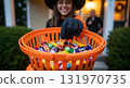 Girl in witch costume holding candy bucket for Halloween 131970735