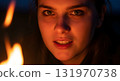 Intense gaze of a young woman illuminated by campfire light. 131970738