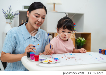 happy mother and toddler girl painting watercolor in paper at home happy mother and toddler girl painting watercolor in paper at home 131971274