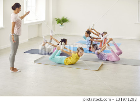 Group of flexible children doing gymnastic exercises on gym floor at sports school Group of flexible children doing gymnastic exercises on gym floor at sports school 131971298