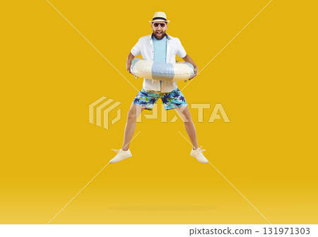 Happy man with inflatable beach ring enjoying summer vacation and jumping on trampoline Happy man with inflatable beach ring enjoying summer vacation and jumping on trampoline 131971303