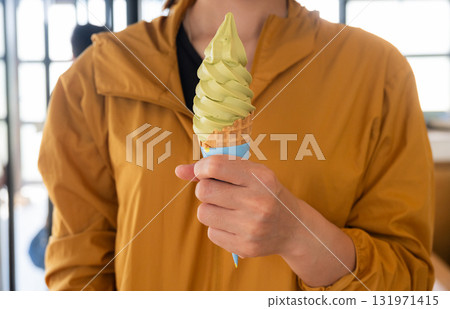Cropped shot view of woman holding a green tea ice cream. Ice creams are dairy-based frozen foods usually consumed as snacks or desserts. 131971415