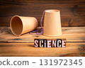 Science experiment concept with two paper cups connected by string and wooden block letters spelling 131972345