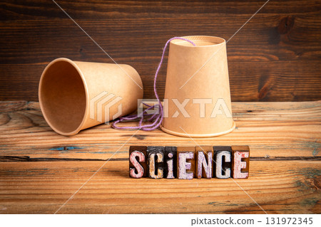 Science experiment concept with two paper cups connected by string and wooden block letters spelling Science experiment concept with two paper cups connected by string and wooden block letters spelling 131972345