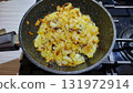 Chopped onions frying in a pan on the stovetop during evening meal preparation at a cozy home kitchen 131972914