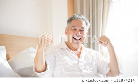 微笑的老人在明亮的臥室裡揮舞拳頭 微笑的老人在明亮的臥室裡揮舞拳頭 131974214