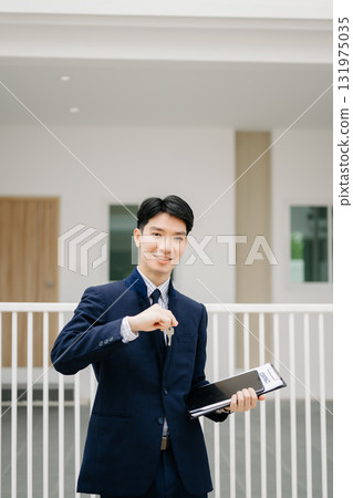Asian man Real estate broker agent showing a house detail in her file to the young Asian couple lover looking and interest to buy it. 131975035