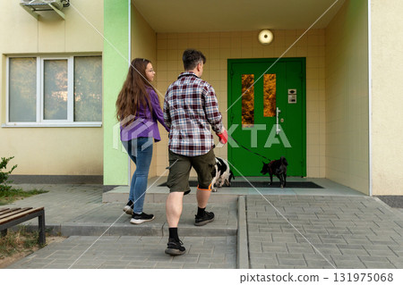 Father and daughter walking dogs toward green apartment door Father and daughter walking dogs toward green apartment door 131975068