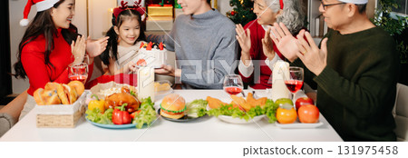 Happy Asian family celebrating Christmas together at home. Real people wearing Santa hats, exchanging gifts, smiling with joy, festive dinner, love, and holiday cheer. Happy Asian family celebrating Christmas together at home. Real people wearing Santa hats, exchanging gifts, smiling with joy, festive dinner, love, and holiday cheer. 131975458